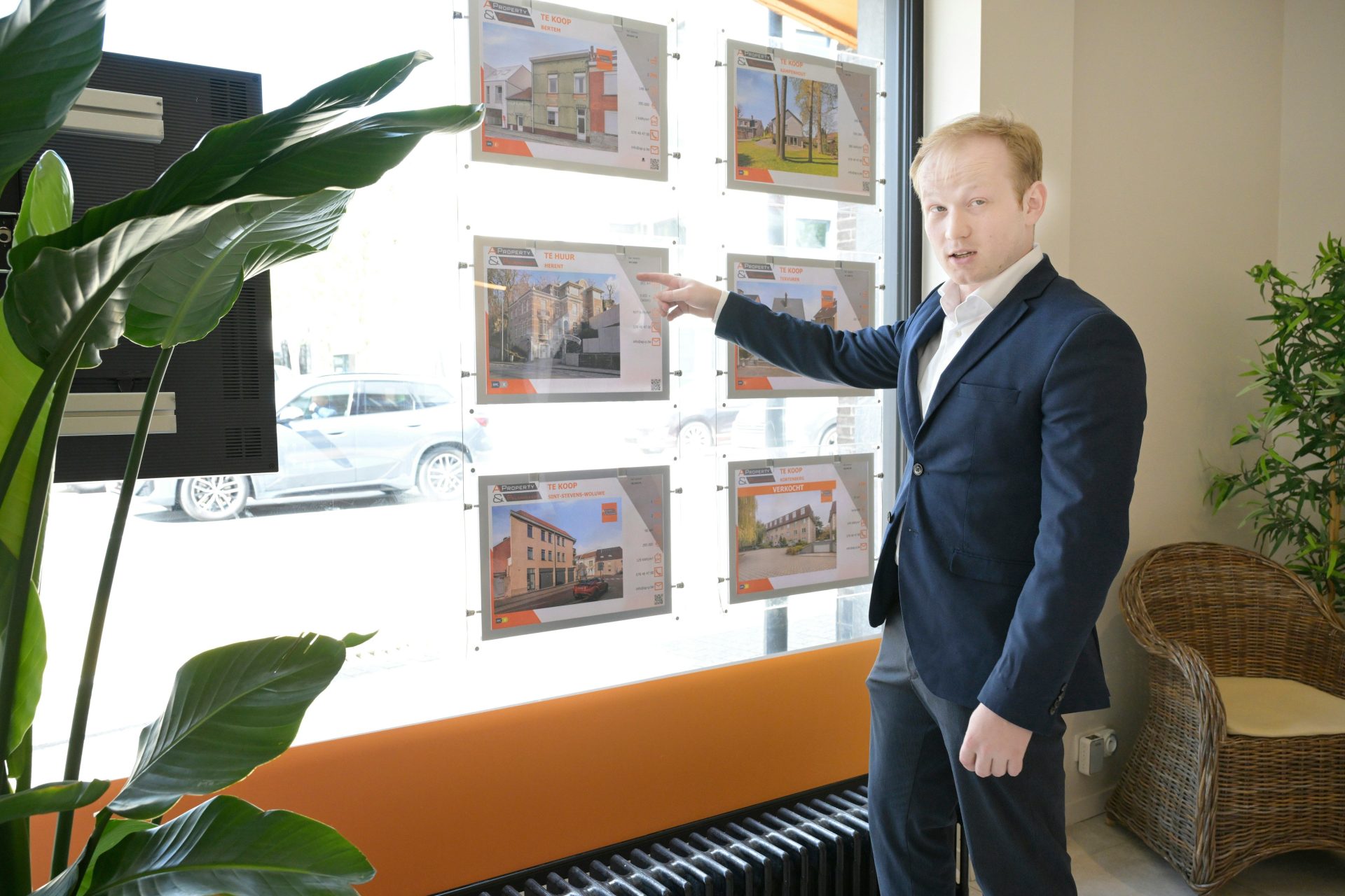 Real estate agent pointing at property listings in office window.